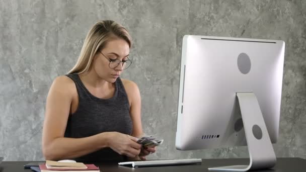 Jeune femme assise et comptant l'argent dans le bureau . — Video