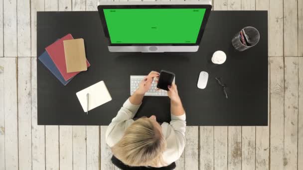 Giovane donna bionda messaggiando messaggio su smartphone sulla sua postazione di lavoro. Visualizzazione finto schermo verde . — Video Stock