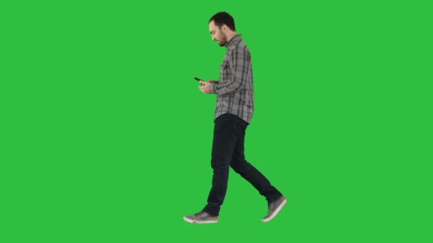 Smart casual mladík chůzi a čtení zpráv na mobilní telefon na zelené obrazovce, Chroma Key. — Stock video