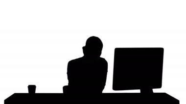 Siluet. Güzel, mutlu, gülümseyen, ofis masasında çalışan genç bir ofis kadını. Resmi olarak çekici, neşeli bir model. Akıllı telefon ve bilgisayar kullanarak, iş saatlerinde arama yaparak..