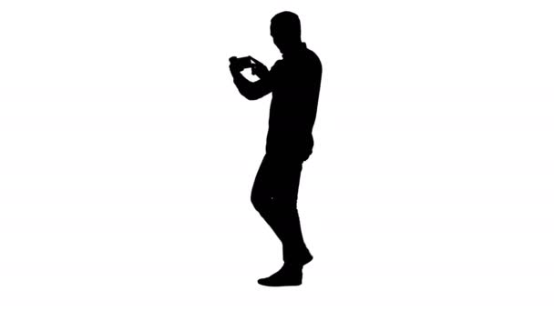 Silhouette Junger Mann fotografiert beim Gehen mit Smartphone. — Stockvideo