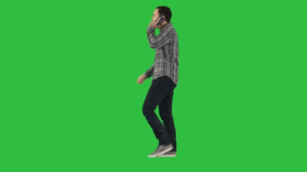 Mladý vousatý muž chodí a mluví na mobilním telefonu na zelené obrazovce, Chroma Key. — Stock video