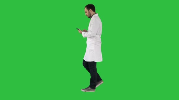 Lékař chůzi a používání mobilního telefonu na zelené obrazovce, Chroma Key. — Stock video