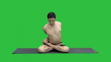 Pratik yoga Adho Mukha Padmasana, ileri Lotus poz Chroma anahtar yeşil ekranda varyasyon bükme bağdaş kurup oturan, sportif güzel genç adam.