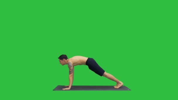 Профиль мускулистого красивого молодого человека, занимающегося спортом, стоящего в йоге вверх, лицом вниз, поза собаки, затем размахивая руками на зеленом экране, хрома-ключ . — стоковое видео