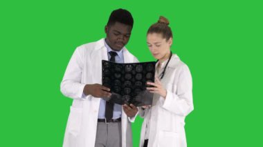 Beyin çalışma ciddi güzel kadın doktor ve afro Amerikalı doktor röntgen Chroma anahtar yeşil ekranda.