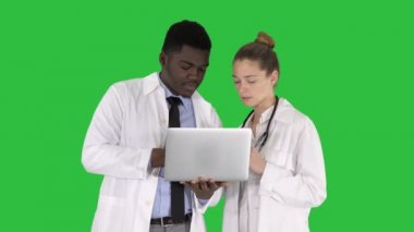 Önünde duran Chroma anahtar yeşil ekranda gri bir dizüstü çalışan tıbbi personel.