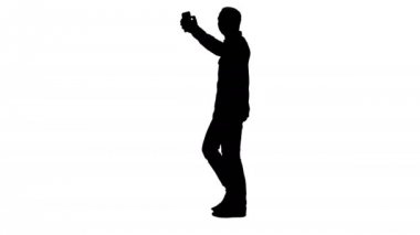 Tam boy portre kenar görünümü. Siluet Mutlu gülümseyen yakışıklı sakallı genç adam selfie çekiyor. 4K çözünürlükte profesyonel atış. 004. Kullanabilirsin, mesela. Ticari videonuzda