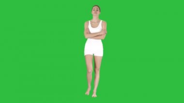 Gülümseyen katlanmış silah ile yürüyüş spor kadın ve kameraya Chroma anahtar yeşil ekran arıyorum.