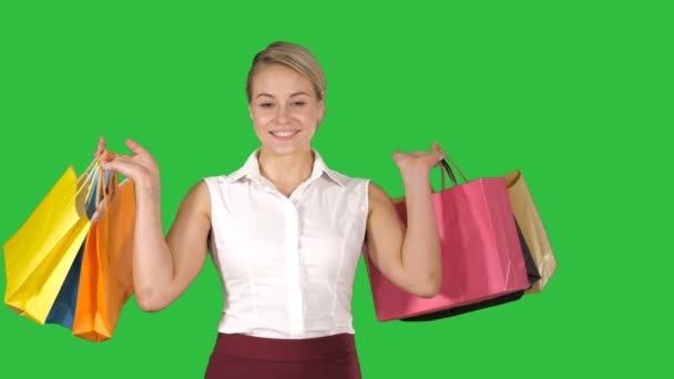 Mujer joven caminando y sosteniendo bolsas de compras mientras hace algunas compras en una pantalla verde, Chroma Key . — Vídeo de stock