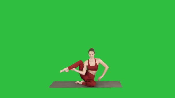 Sporty yogi girl doing fitness practice, stretches, yoga asana Parivritta Kraunchasana on a Green Screen, Chroma Key. — Stock Video