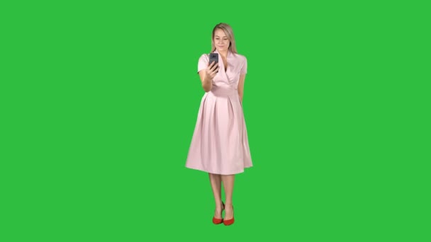 Blond žena v růžové oblečení, přičemž selfie a chůzi na zelené obrazovce, Chroma Key. — Stock video