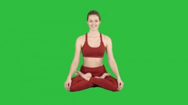 Kadın pratik yoga, gülümseyen genç Padmasana yaparken egzersiz, Lotus poz Chroma anahtar yeşil ekranda.