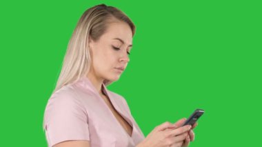Chroma anahtar yeşil ekranda Smartphone cep telefonu ile mesaj gönderme neşeli genç kadın portresi.