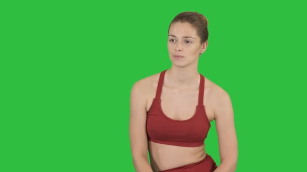 Vacker flicka i sportkläder som lyssnar på någon prata med henne på en grön skärm, Chroma Key. — Stockvideo