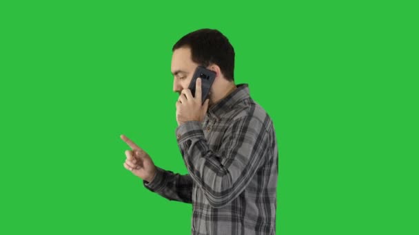 Portrait latéral d'un étudiant heureux marchant et parlant sur un téléphone portable sur un écran vert, Chroma Key . — Video