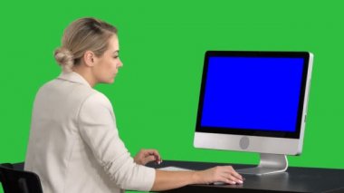 Ofiste masa başında oturan çalışan genç kadın ekrana Chroma anahtar yeşil ekran arıyorum. Mavi ekran Mock-up.