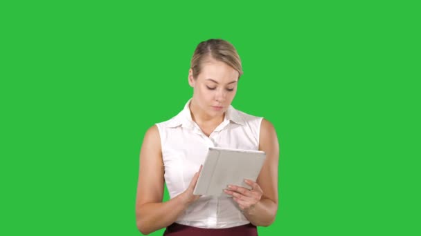 Charmante schöne Frau mit blonden Haaren, sie verwendet ihr digitales Tablet zum Betrachten von Fotos und Videos auf einem grünen Bildschirm, Chroma-Taste. — Stockvideo