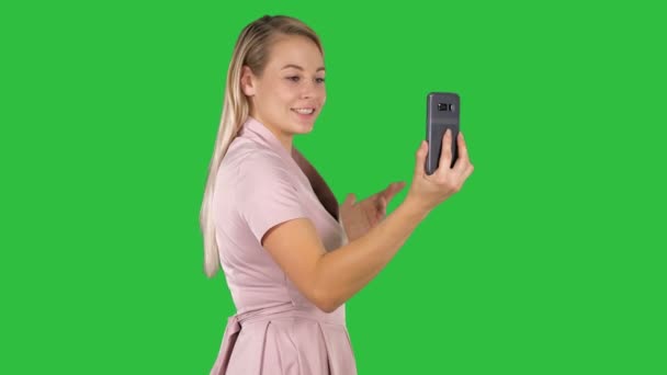 媒体は サイドビューを撮影しました クロマキー グリーン画面で彼女のスマート フォンでビデオ通話のピンクのドレスの女性 プロは 解像度で撮影 005 あなたの商業ビデオで例えば使用できるあなた — ストック動画