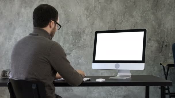 Bearded young businessman woking on computer. White Display. — Stock Video