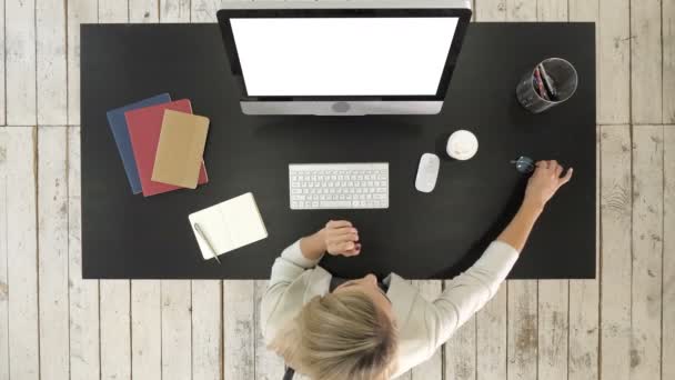 Frau setzt Brille auf, während sie Computer benutzt. weißes Display. — Stockvideo