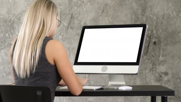 女商人坐在办公室的办公桌前, 在桌面显示器上工作。白色显示屏. — 图库视频影像