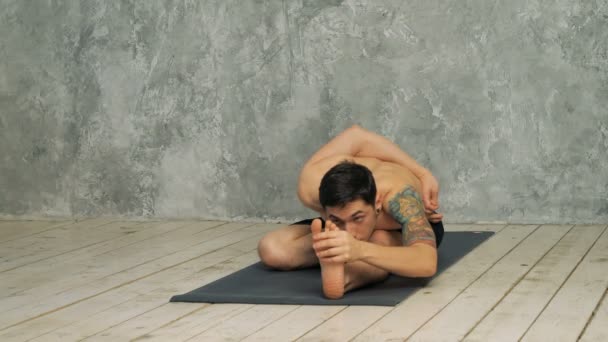 Man practicing yoga in half hero stretch pose — Stock Video