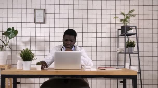 Joven médico afroamericano en el trabajo, con portátil . — Vídeos de Stock