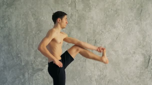 Sportsman fare esercizio fisico, flessione in variazione di Utthita Hasta Padangusthasana, Dandayamana-Janushirasana, Standing Head to Knee Bikram postura . — Video Stock