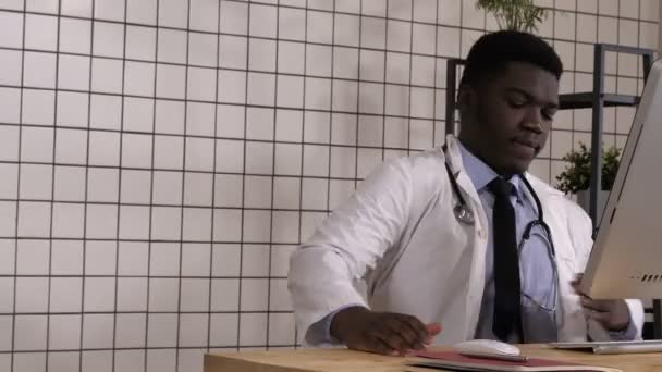 Entrar al médico africano sentado en el escritorio y empezar a trabajar . — Vídeos de Stock