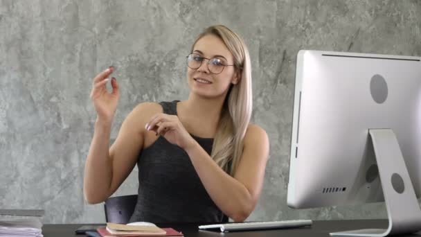 Schattig zakenvrouw kijkt naar de camera en spreekt in haar kantoor. — Stockvideo