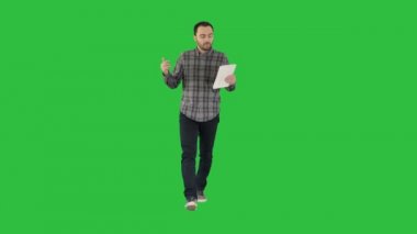 Rahat tablet ile yürüyüş ve Chroma anahtar yeşil ekran video konferans konuşan adam.