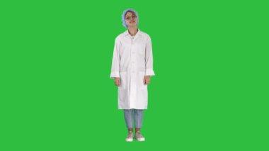 Doktor kadın el HIPS, ayakta, rahat ve gülümseyen, çok olumlu ve neşeli bir yeşil ekranında, Chroma Key ile.