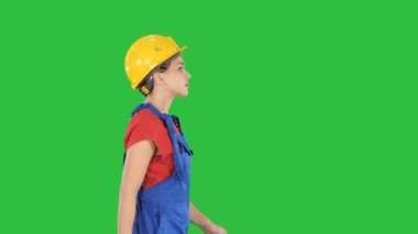 Sarı kask yeşil ekranda Chroma Key yürüyen genç kadın.