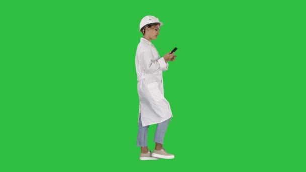 クロマキー緑色の画面の上を歩いてのスマート フォンを使用して女性の科学者. — ストック動画