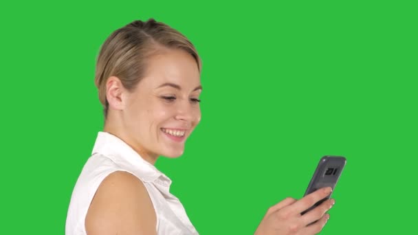 Junge schöne Frau schreibt eine SMS auf einen grünen Bildschirm, Chroma-Taste. — Stockvideo