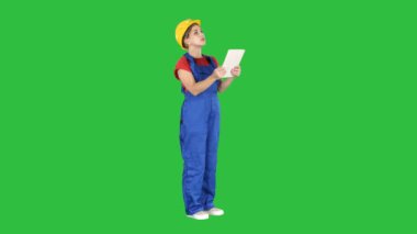 Kadın mühendisi olarak sarı kask yeşil ekranda Chroma Key bina yapımı için denetlerken tablet bilgisayara arıyor.