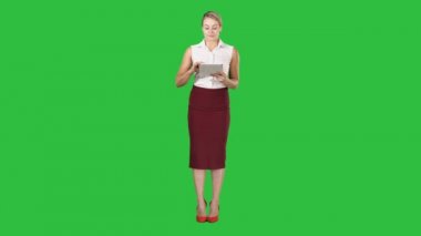 Mutlu genç bayan ayakta kullanarak tablet ve kamera için Chroma anahtar yeşil ekran arıyorum.
