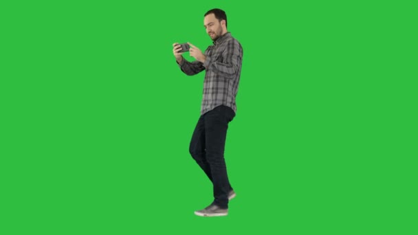 Ung man att ta foto med smartphone medan promenader på en grön skärm, Chroma Key. — Stockvideo