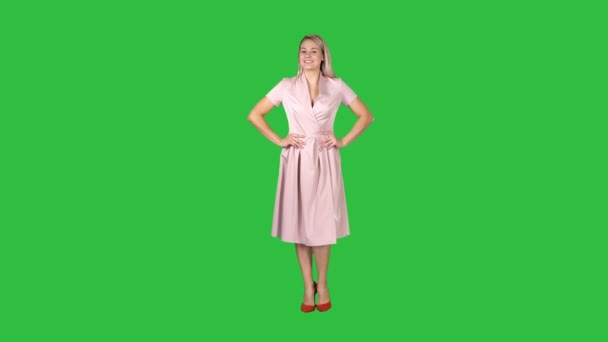 Γυναίκα στο φόρεμα με τα χέρια στους γοφούς περπάτημα ενώ κοιτάζοντας την κάμερα σε μια πράσινη οθόνη, Chroma Key. — Αρχείο Βίντεο