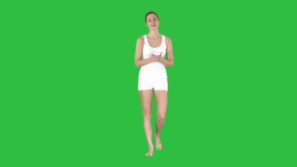 Vrouw in witte sport kleding houden een papieren kopje koffie en praat met de camera op een groen scherm, Chromakey. — Stockvideo