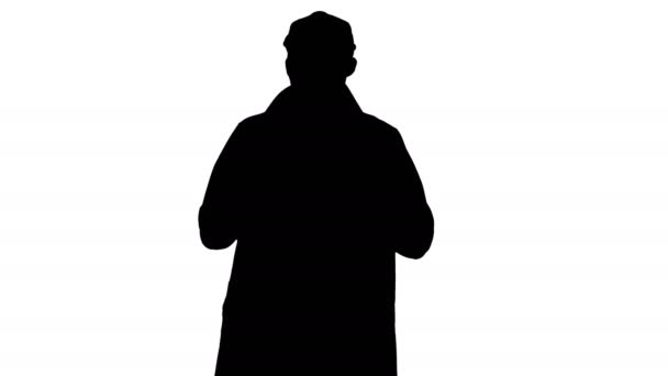 Silhouet van Charming man in trenchcoat lopend en pratend met camera. — Stockvideo