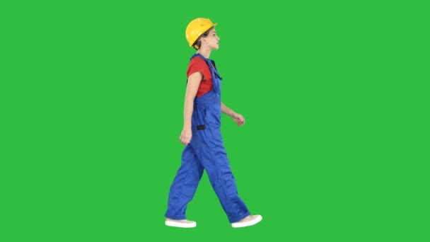 Jeune femme ouvrière de la construction en casque jaune marchant sur un écran vert, Chroma Key . — Video