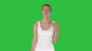 Güzel kız konuşuyor ve yeşil ekranda Chroma Key yürüme atlet giymiş.
