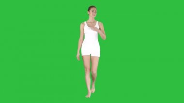 Yürüyüş ve Chroma Key bir yeşil ekranda bir şey üzerinde yan gösteren işaret eden sarışın genç kadın.