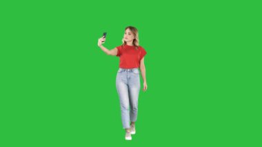 Sevimli seksi kız sarışın kıvırcık saçlı yürüyüş ve selfie Chroma anahtar yeşil ekran yapmak.