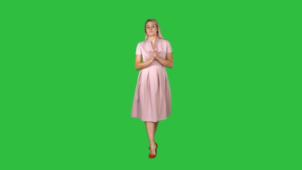 Ευτυχισμένη γυναίκα inpink φόρεμα είναι το περπάτημα προς την κάμερα και μιλάμε για μια πράσινη οθόνη, Chroma Key. — Αρχείο Βίντεο