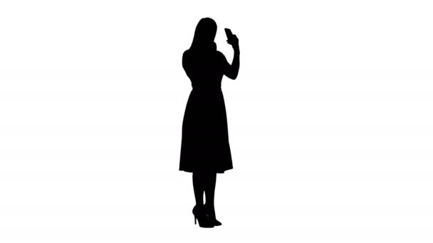 Silhouette Frau, die Lippenstift aufträgt und auf ihr Handy schaut. — Stockvideo