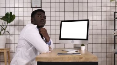 Onun bilgisayar yanında düşünme erkek yakışıklı Afrika doktor. Beyaz ekran.