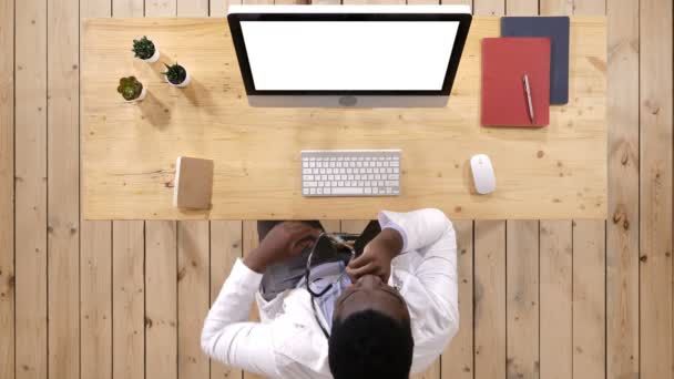 Unavený lékař sedí v přední části monitoru na jeho palubě v ordinaci. Bílý displej. — Stock video
